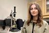 A photograph of Alaa Al-Shaer standing in front of a microscope