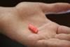 An image showing a hand holding a pink pill