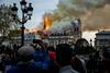 An image showing people watch the landmark Notre-Dame Cathedral burning in central Paris on April 15, 2019