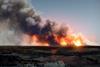 An image showing a landscape where a big wildfire can be seen on the horizon