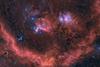 An image showing the Orion stellar neighbourhood as red-glowing dust clouds and hundreds of tiny dots of newly born stars