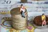 A photograph of male and female figures sat on different sized piles of currency