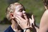 boy having sunscreen applied to his face by his mother