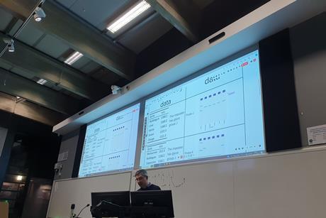Man presenting with two big screens behind